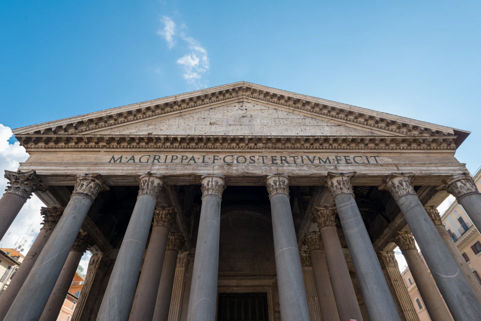 Front view of a historic stone building with large columns and engraved text reading "M AGRIPPA L F COS TERTIVM FECIT" on the facade.