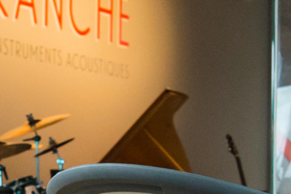 Person playing a guitar with headphones on in a music exhibit. Drums and a sign reading "Unplugged" on display in the background.