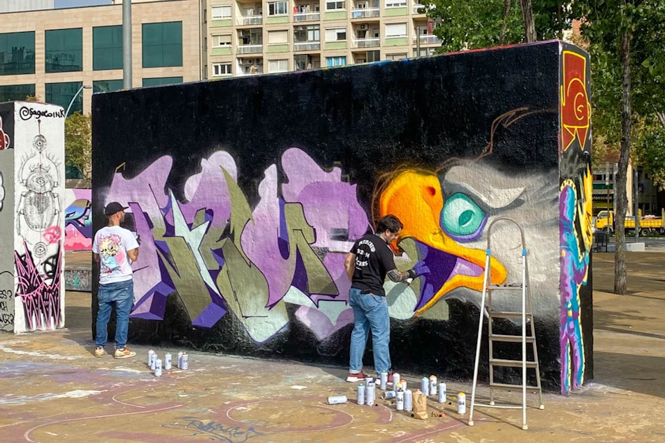 Street artist in the process of creating their work on a city wall.