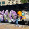 Gadekunstner i færd med at skabe deres arbejde på en bymur.