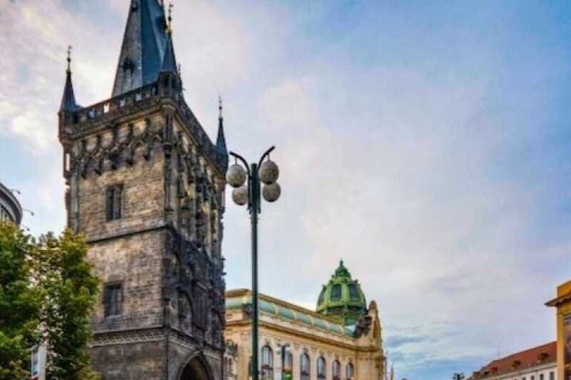 部分的に曇った空の下に緑のドームがある華やかな建物の隣に尖った尖塔がある歴史的な石造りの塔。