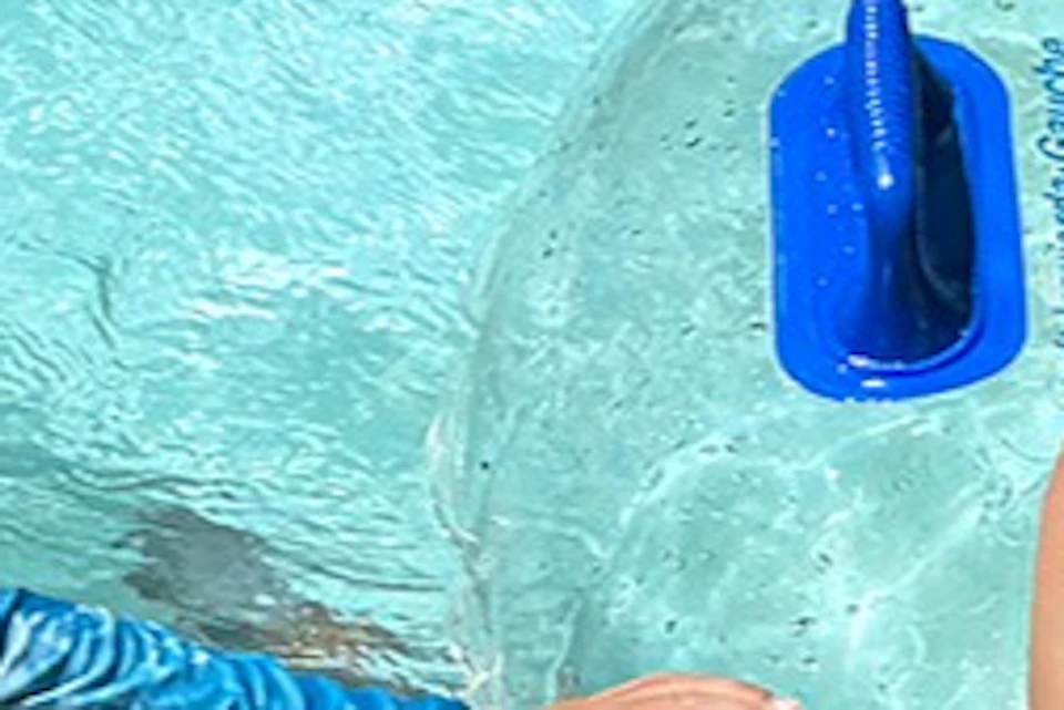 Two children smiling and playing in an outdoor pool with clear inflatable tubes labeled "KUZA".