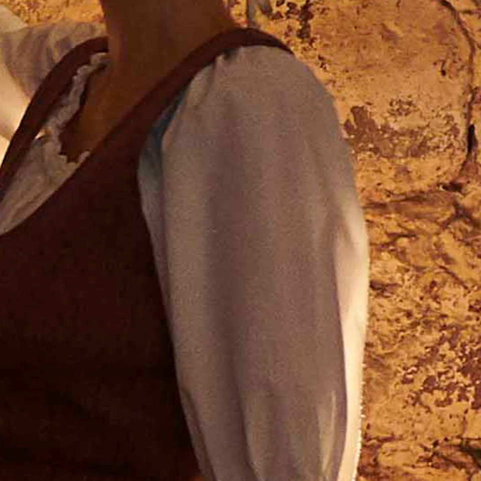 Person in historical attire walking with a lantern in a dimly lit room with framed portraits on a stone wall.