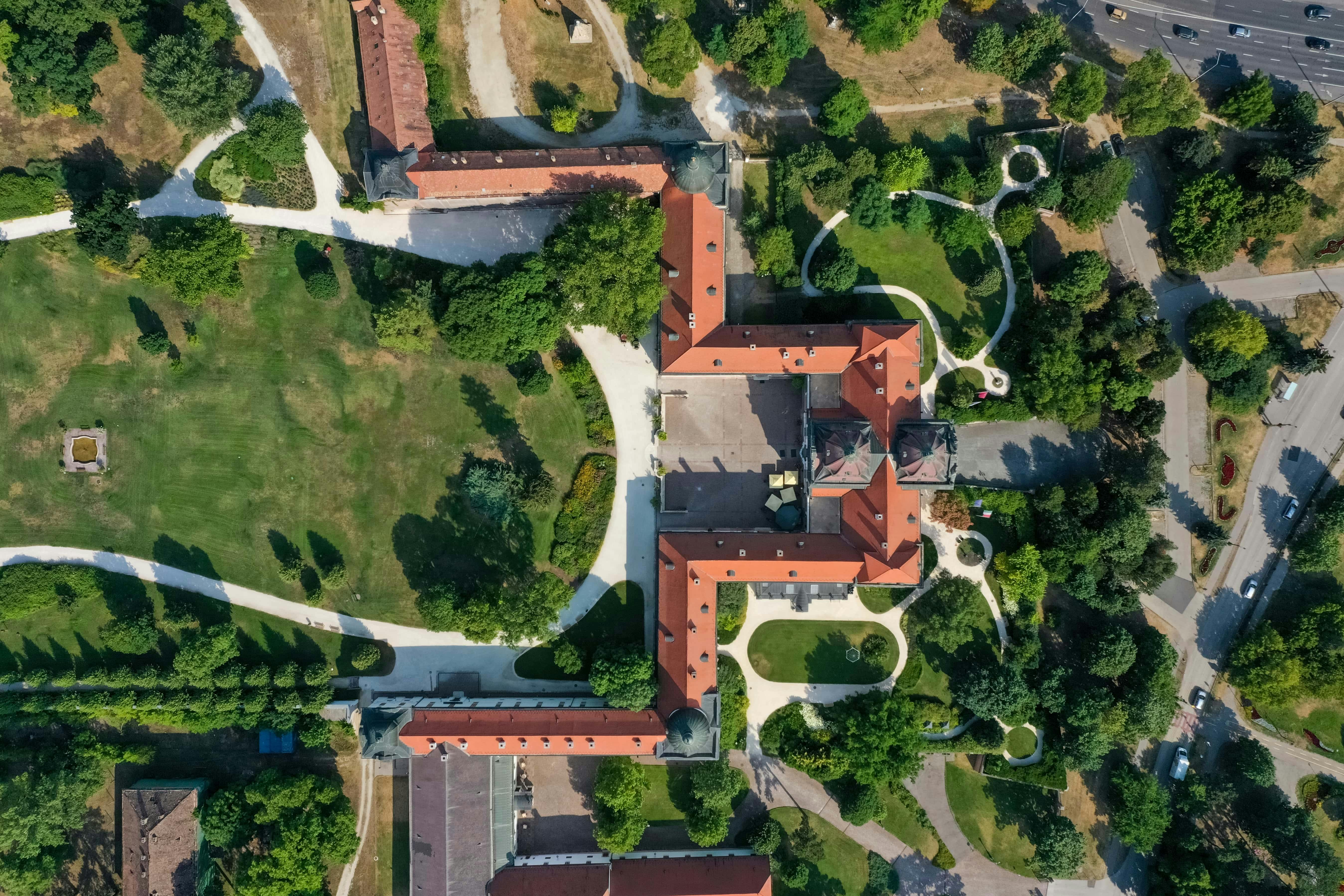 붉은 지붕의 건물, 통로 및 주변 녹지 공간과 나무가 있는 단지의 공중 전망.