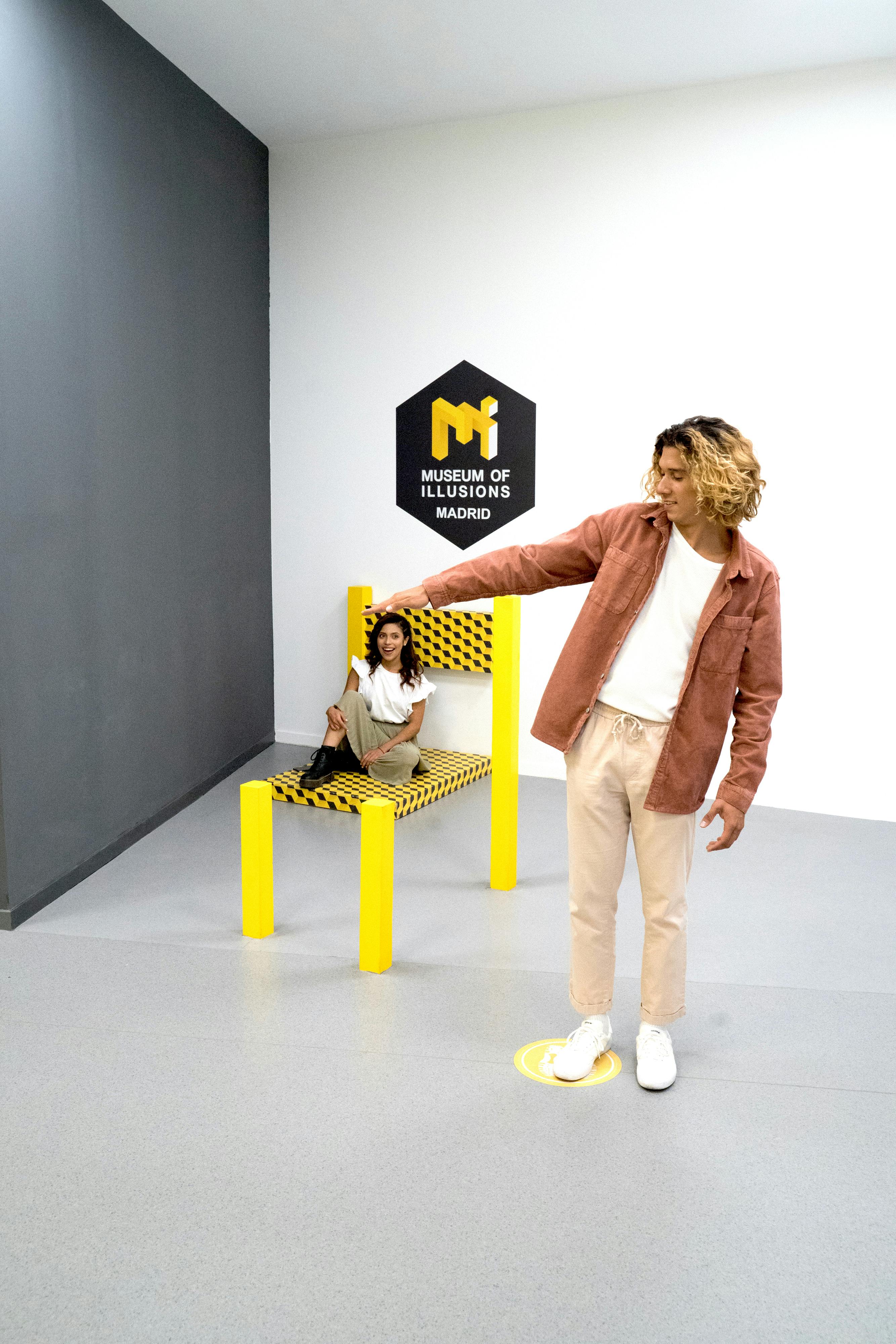 马德里幻觉博物馆（ Museum of Illusions Madrid ）有两人。 一个女人坐在幻术椅上，一个男人站着，似乎指着她。