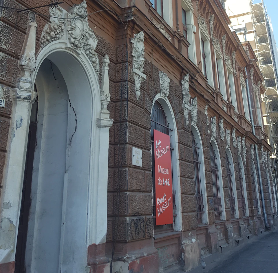 Ornate, historic building with arched windows and a sign reading "Art Museum" in multiple languages.