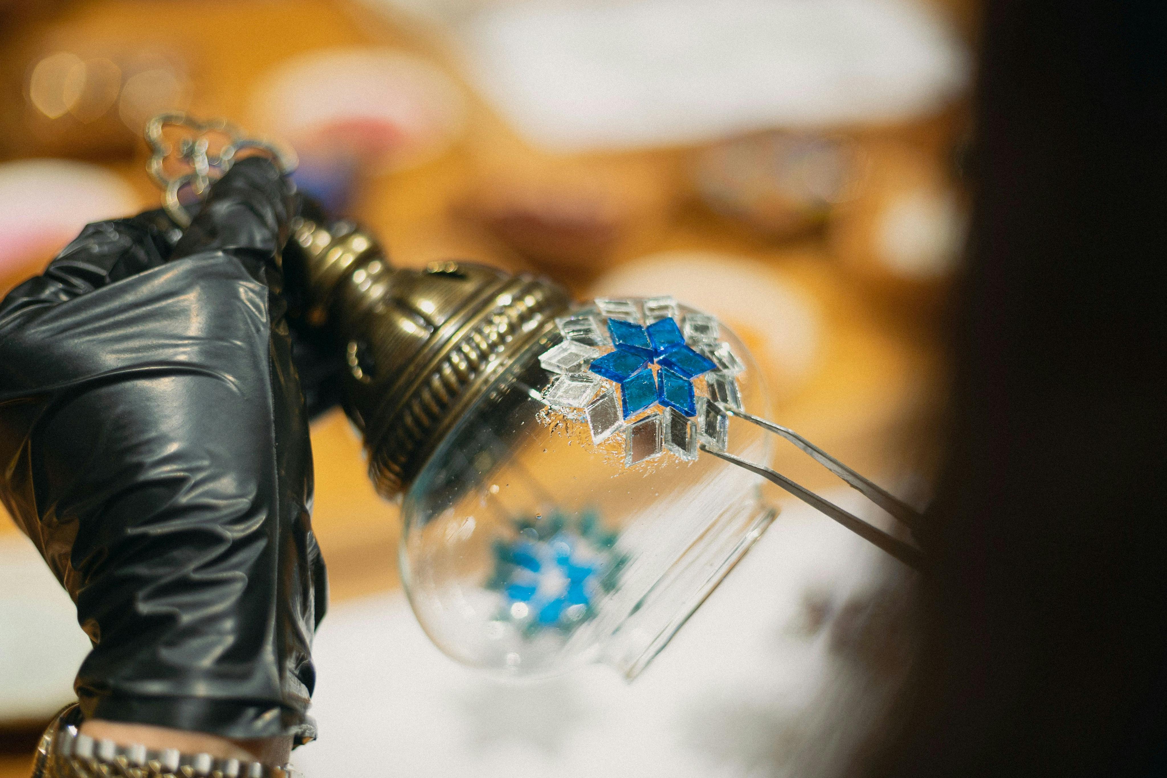 一个戴着黑色手套的人在玻璃球上放置蓝色马赛克的特写镜头。