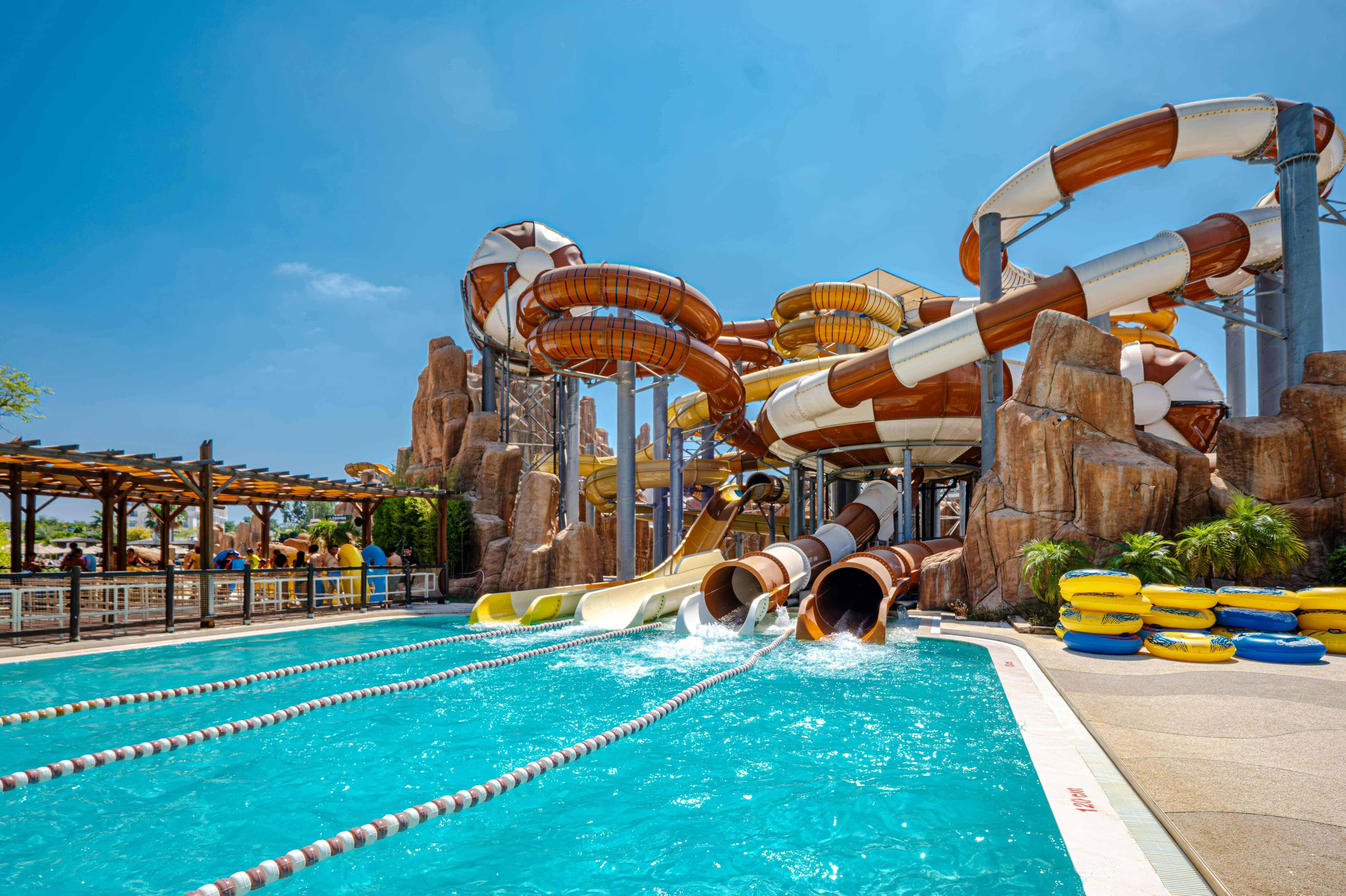 A water park featuring multiple twisty water slides ending in a clear blue pool under a bright sky.