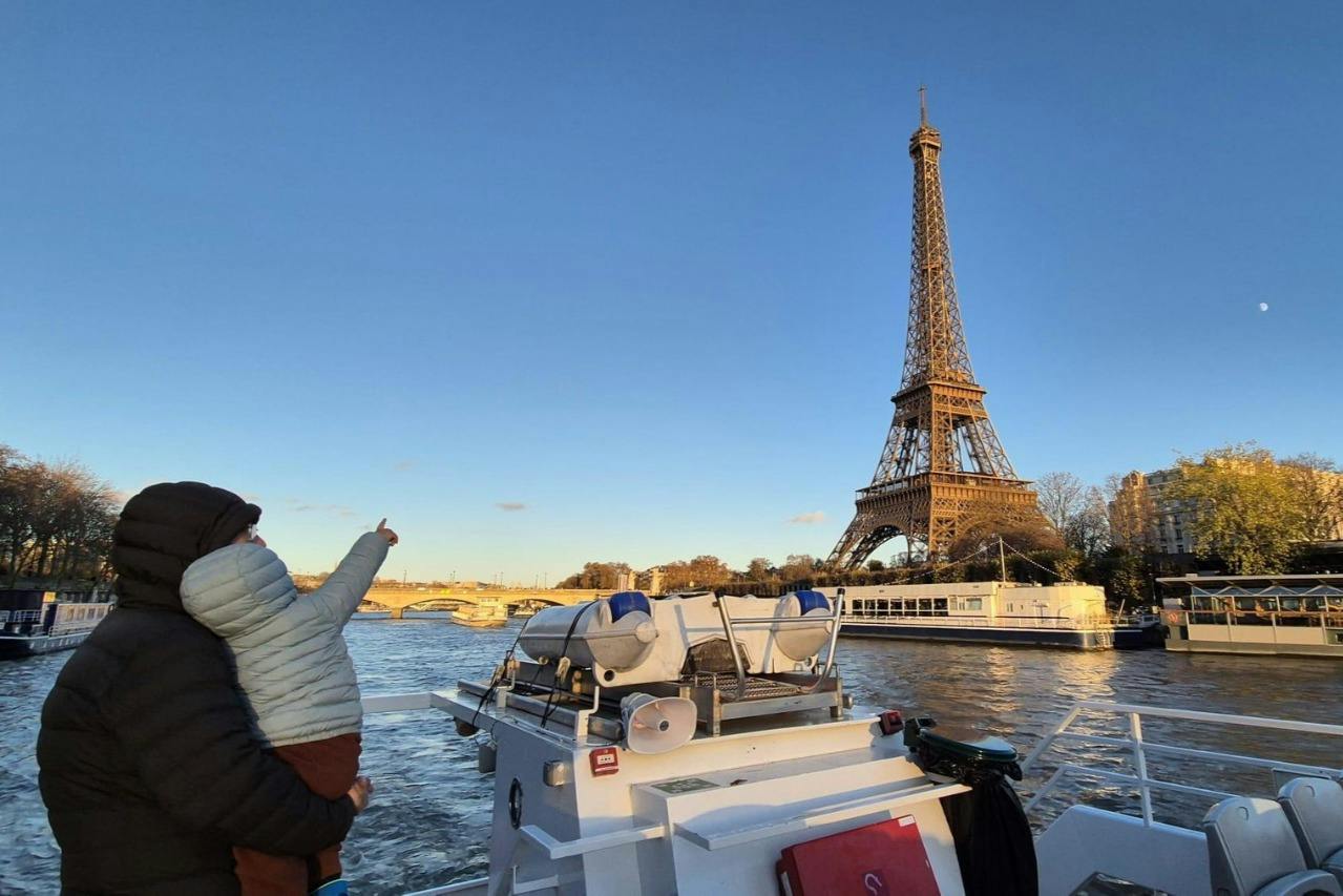Family enjoying the Seine river sightseeing cruise with kids seeing the Eiffel Tower