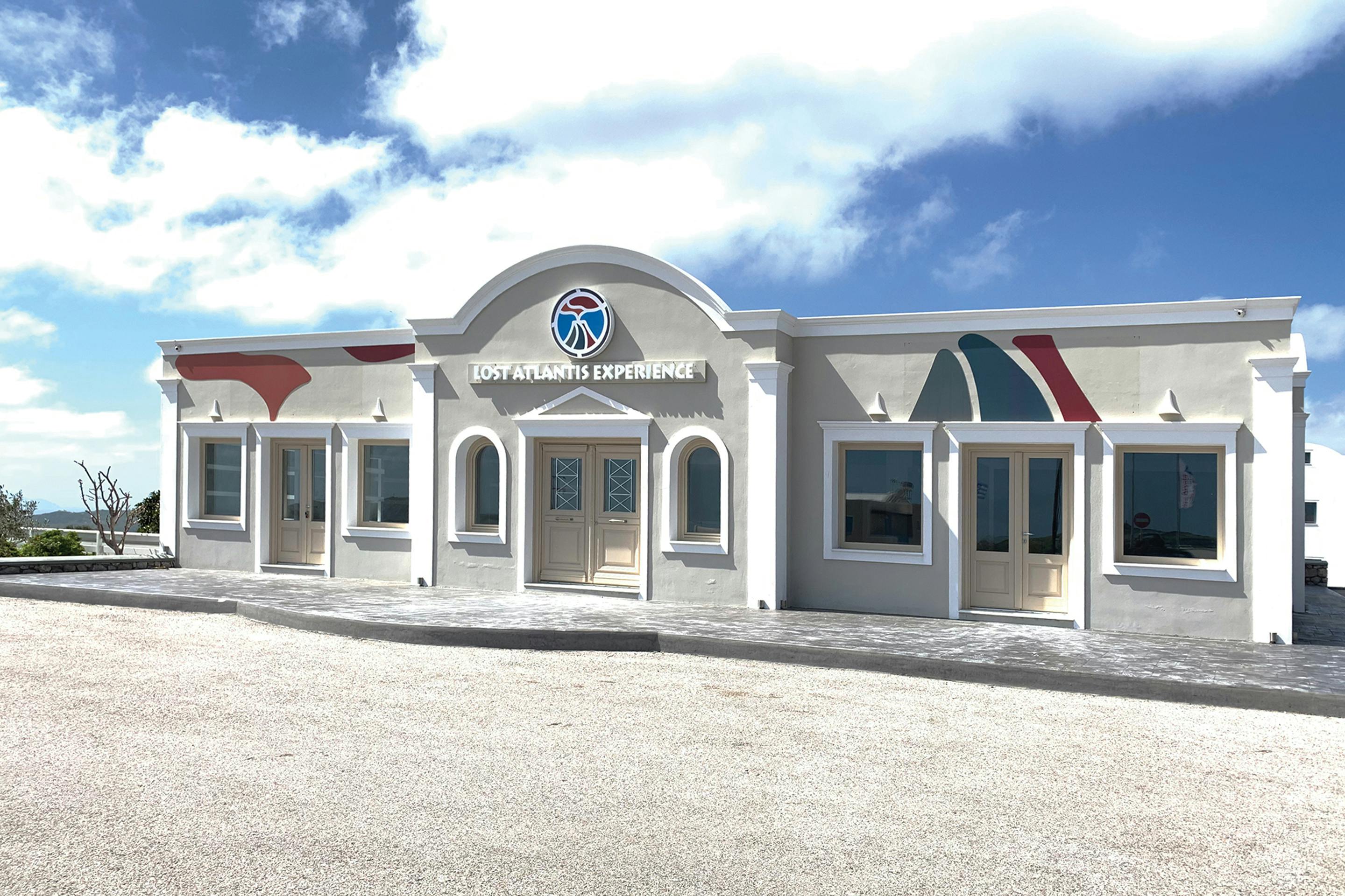A light-colored building with &#34;Lost Atlantis Experience&#34; above the entrance, featuring arched doorways and colorful wall accents.
