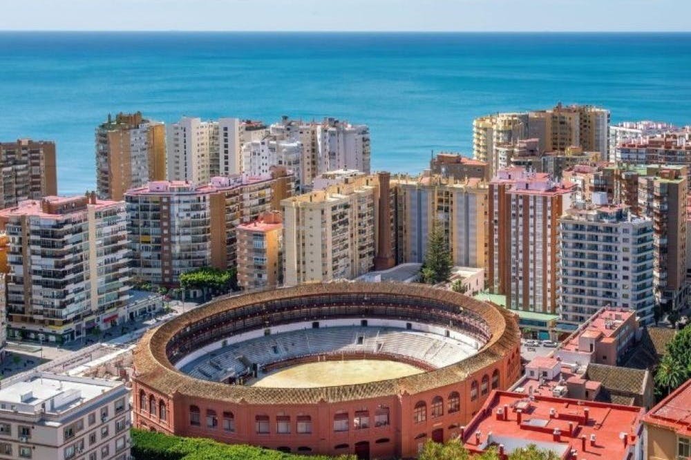 鸟瞰斗牛场，周围环绕着高层建筑，背景中可以看到大海。