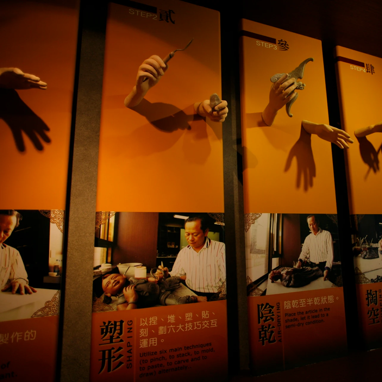 A display showing sculpting steps with hands holding clay and photos of artisans working, accompanied by descriptive text.