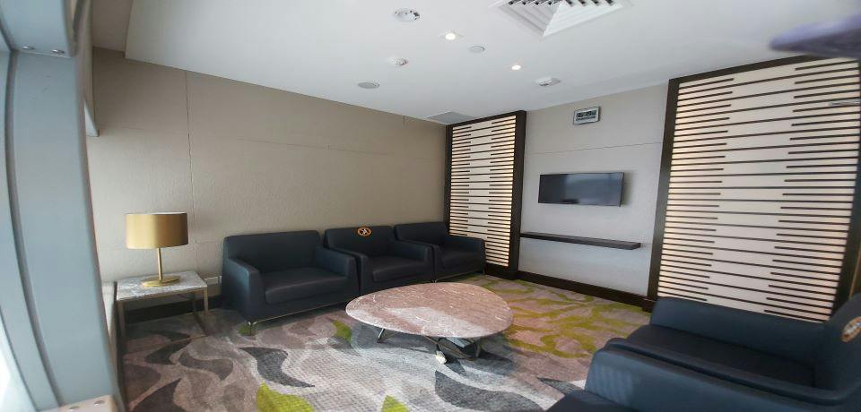 Modern lounge area with dark sofas, a marble coffee table, a wall-mounted TV, and a decorative panel.