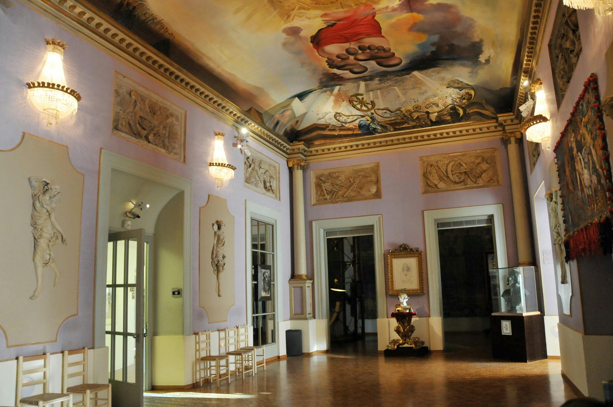 複雑な天井画、古典的な壁のレリーフ、彫刻、大きな出入り口に近い空の椅子があるミュージアムルーム。