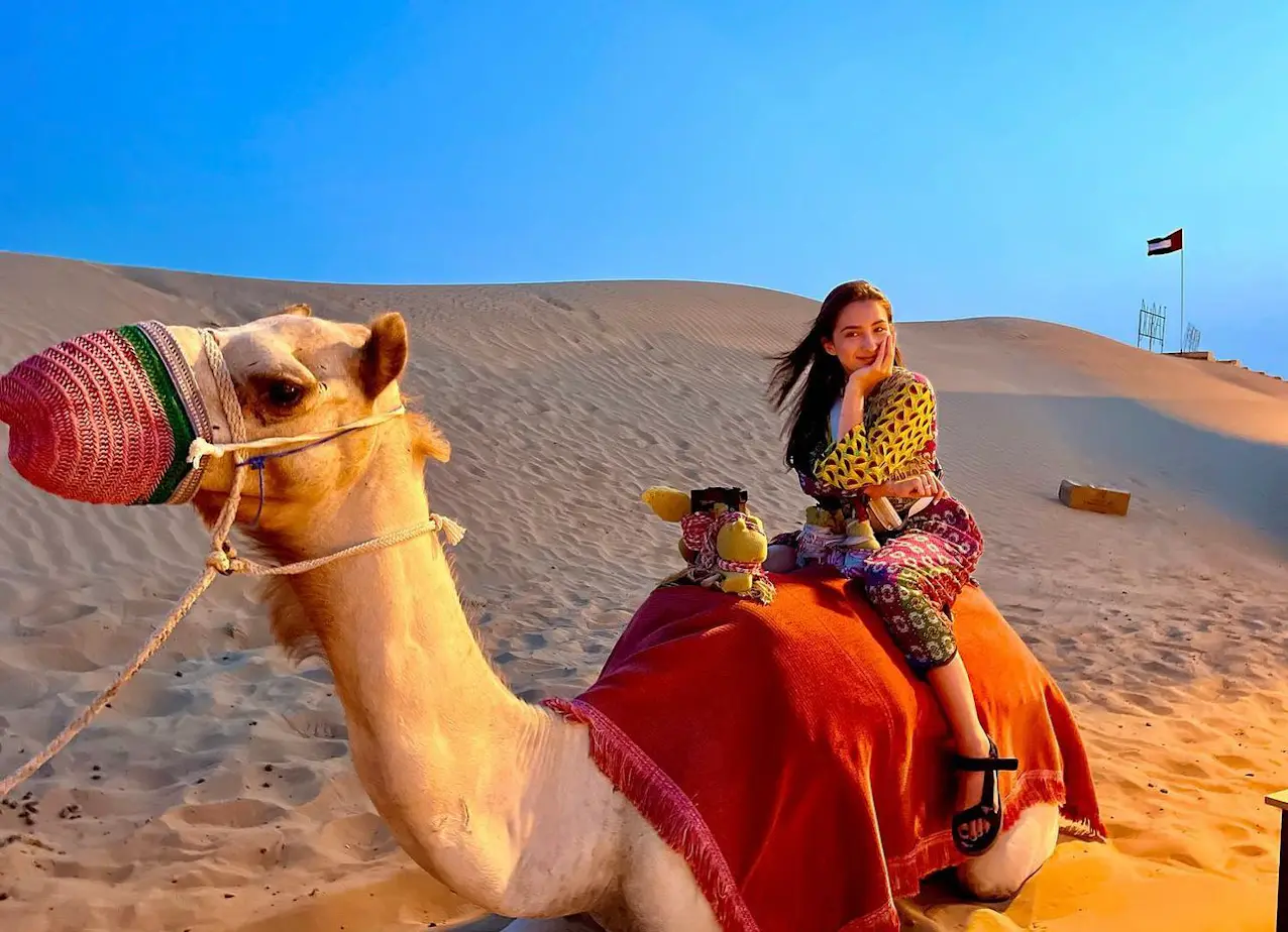Tourist riding a camel during a desert safari in Dubai at sunset