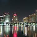 Je ziet Miami vanaf het water: hoge gebouwen, barco's en een schitterend stedelijk landschap verlicht met licht.