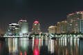 Anochece en Miami desde el agua: edificios altísimos, barcos y un brillante paisaje urbano iluminado con luces.