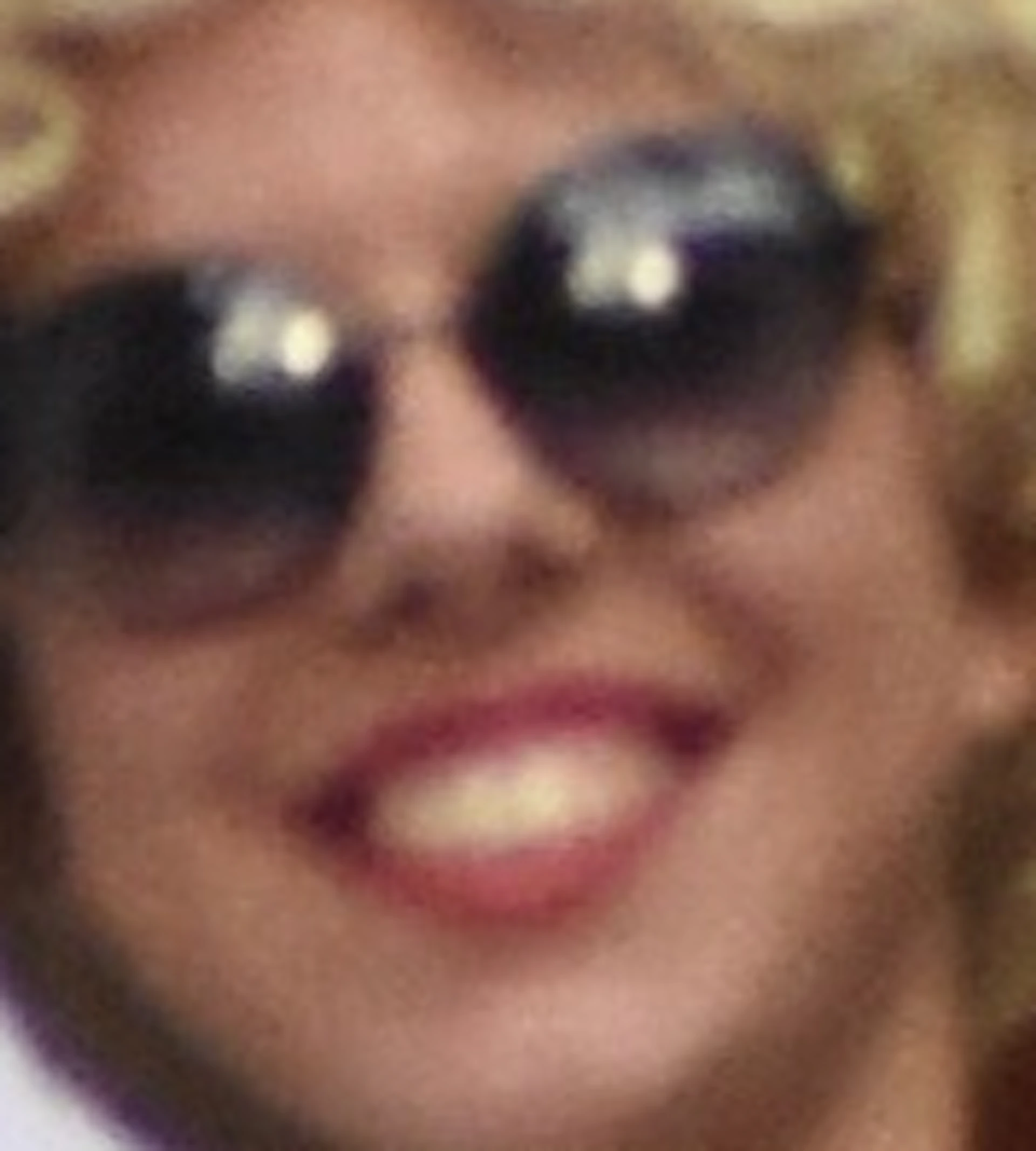 A person in a white dress and blonde wig waves on a balcony under a sign for the Erotic Museum in Barcelona.