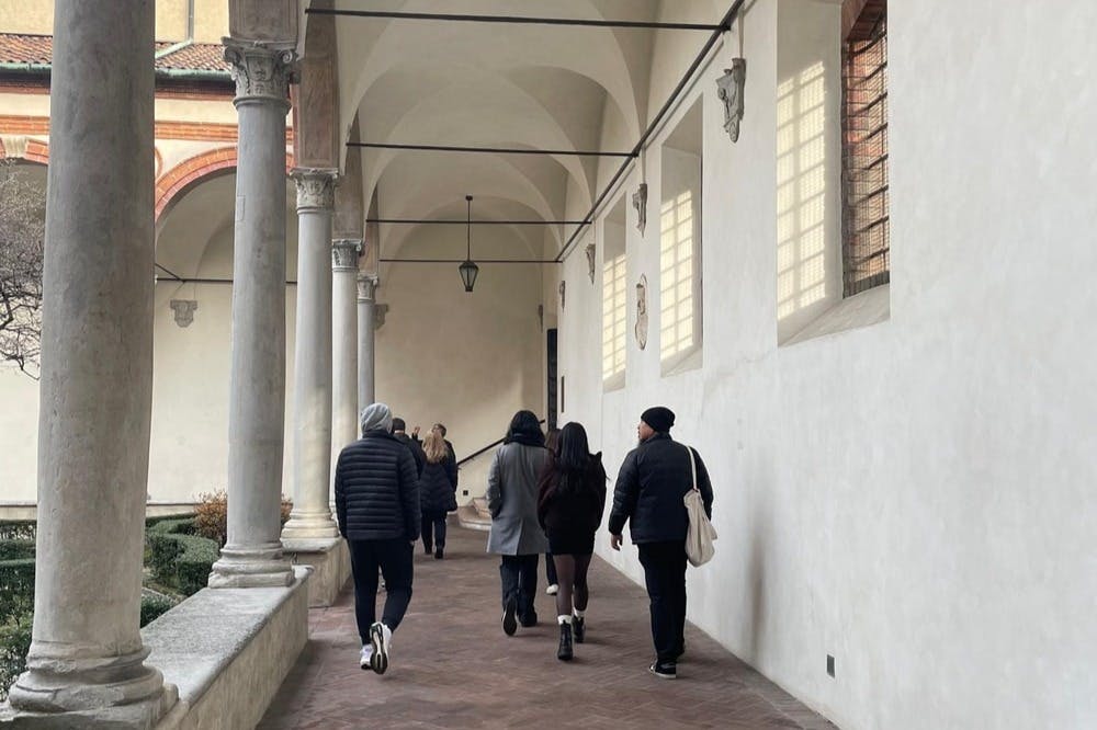 人们穿着冬季服装，穿过柱子和高天花板的拱形走廊。