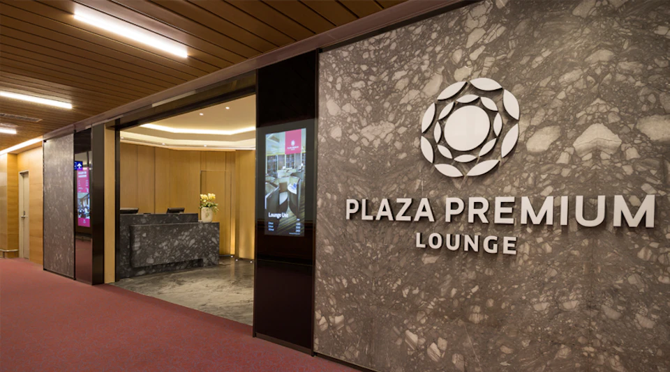 Entrance of the Plaza Premium Lounge with a marble wall, logo, and reception desk visible inside.