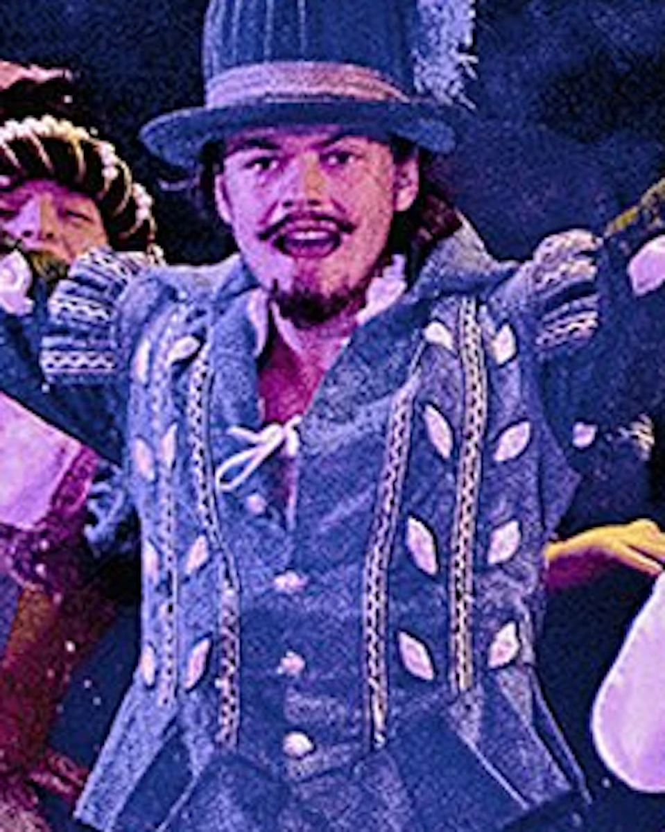 Colorful performers in period costumes on stage above a medieval castle scene with the text 'Puy du Fou España, El Parque.'