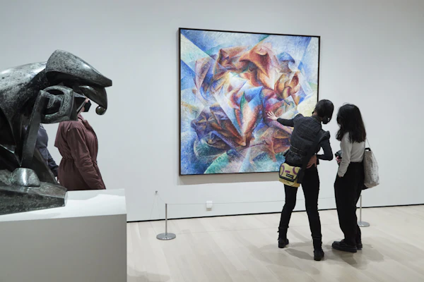 To personer i et galleri beundrer et abstrakt, farverigt maleri; en skulptur er delvist synlig i forgrunden.