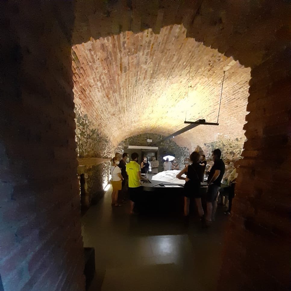 People gathered around a large table under an arched brick ceiling in a dimly lit room.