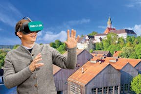 Visitante com óculos de realidade virtual em frente ao Mosteiro de Andechs