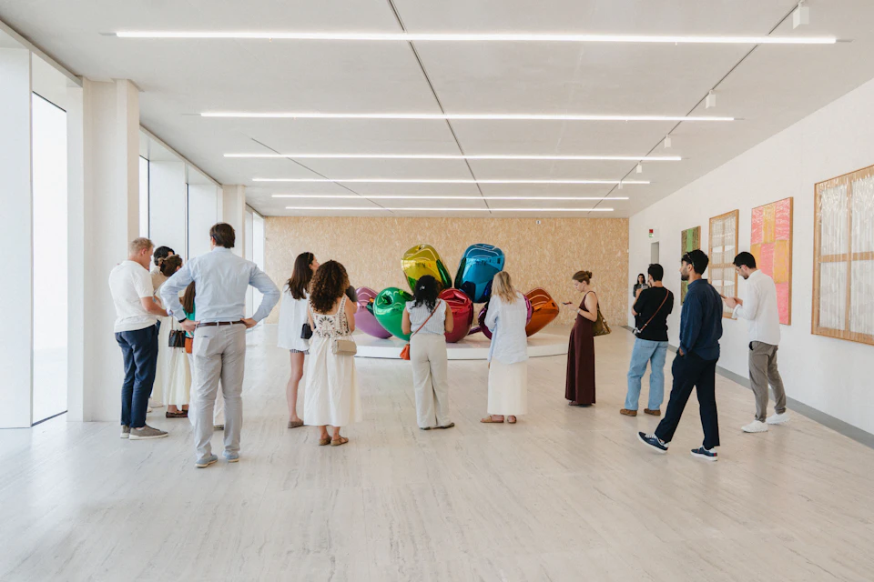 A group of people looking at a colourful, balloon-like sculpture in a modern art gallery with bright lighting.