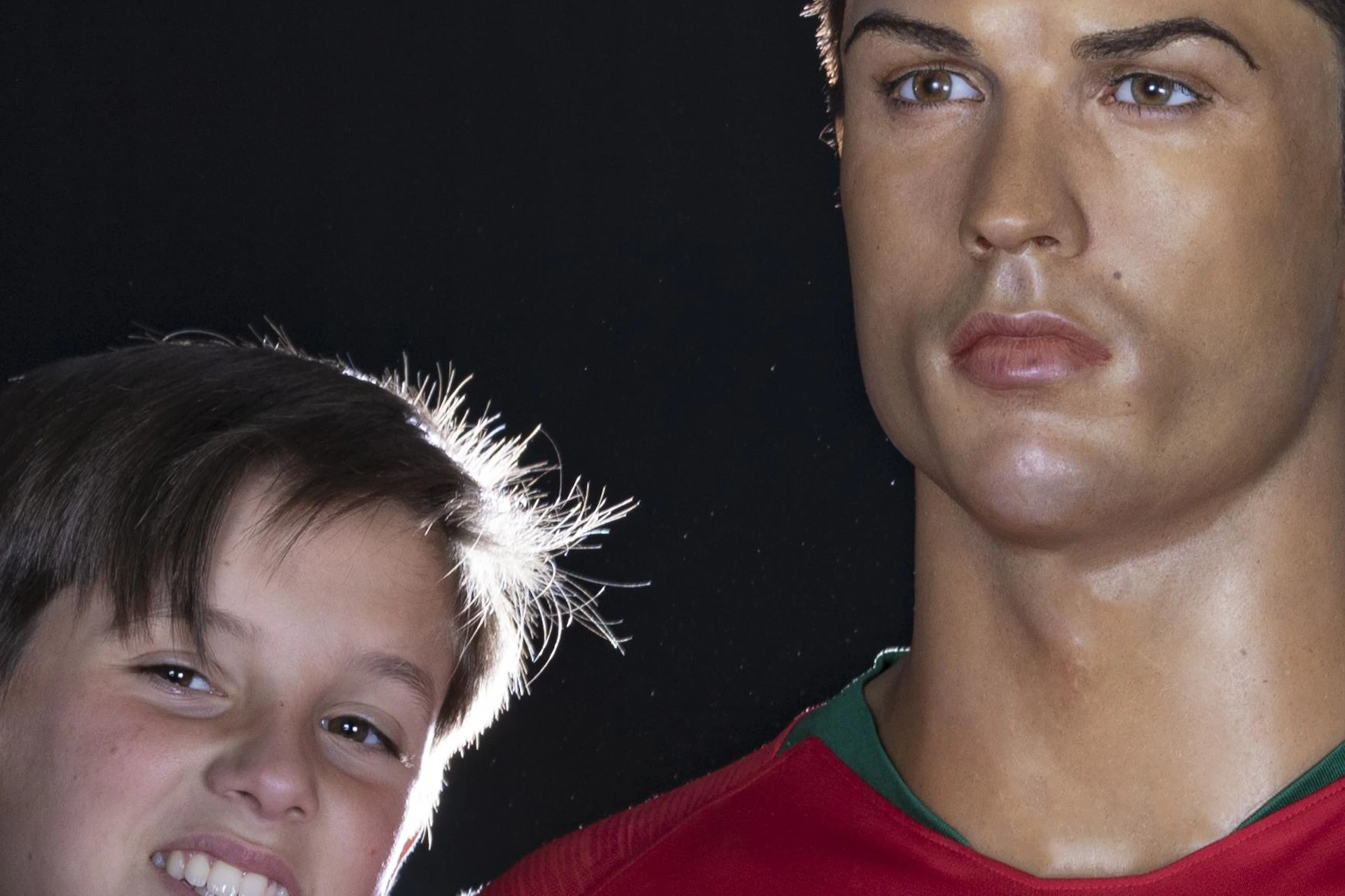 A young person takes a selfie with a sports figure wax statue wearing a red jersey with a Portugal emblem.