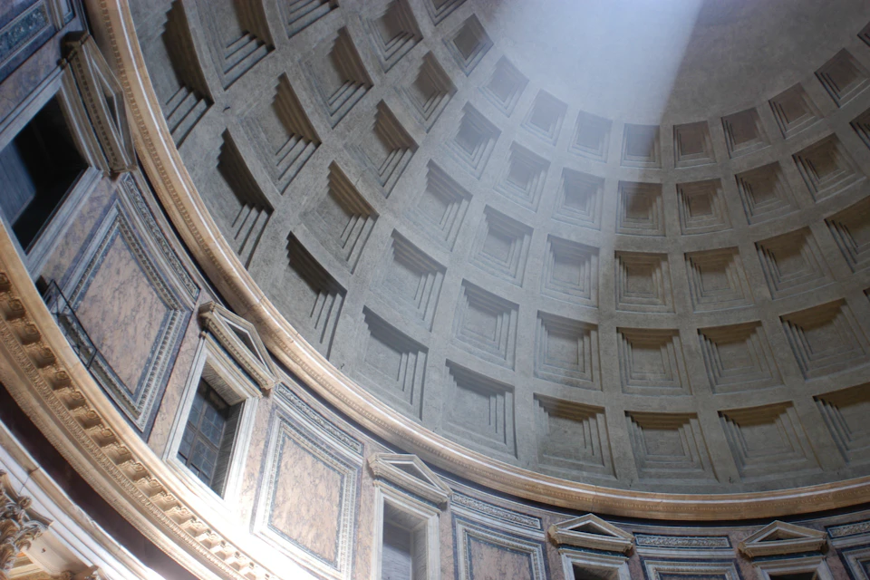 Sunlight beams through the oculus of the Pantheon, illuminating the coffered dome and ornate interior wall details.