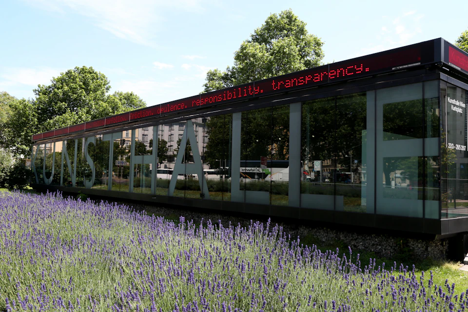 A building with large reflective windows, an LED sign above, and a foreground of blooming lavender plants.