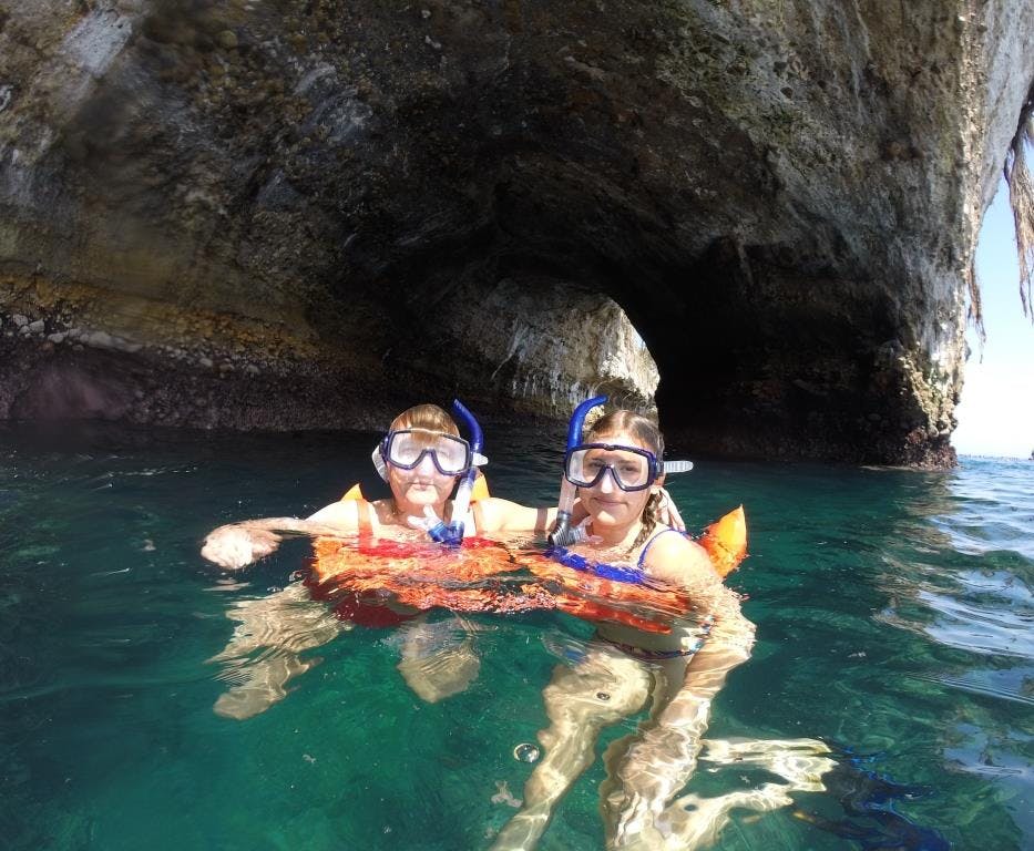 동굴 입구 근처 수면에 스노클링 장비를 착용한 두 사람이 떠 있습니다.