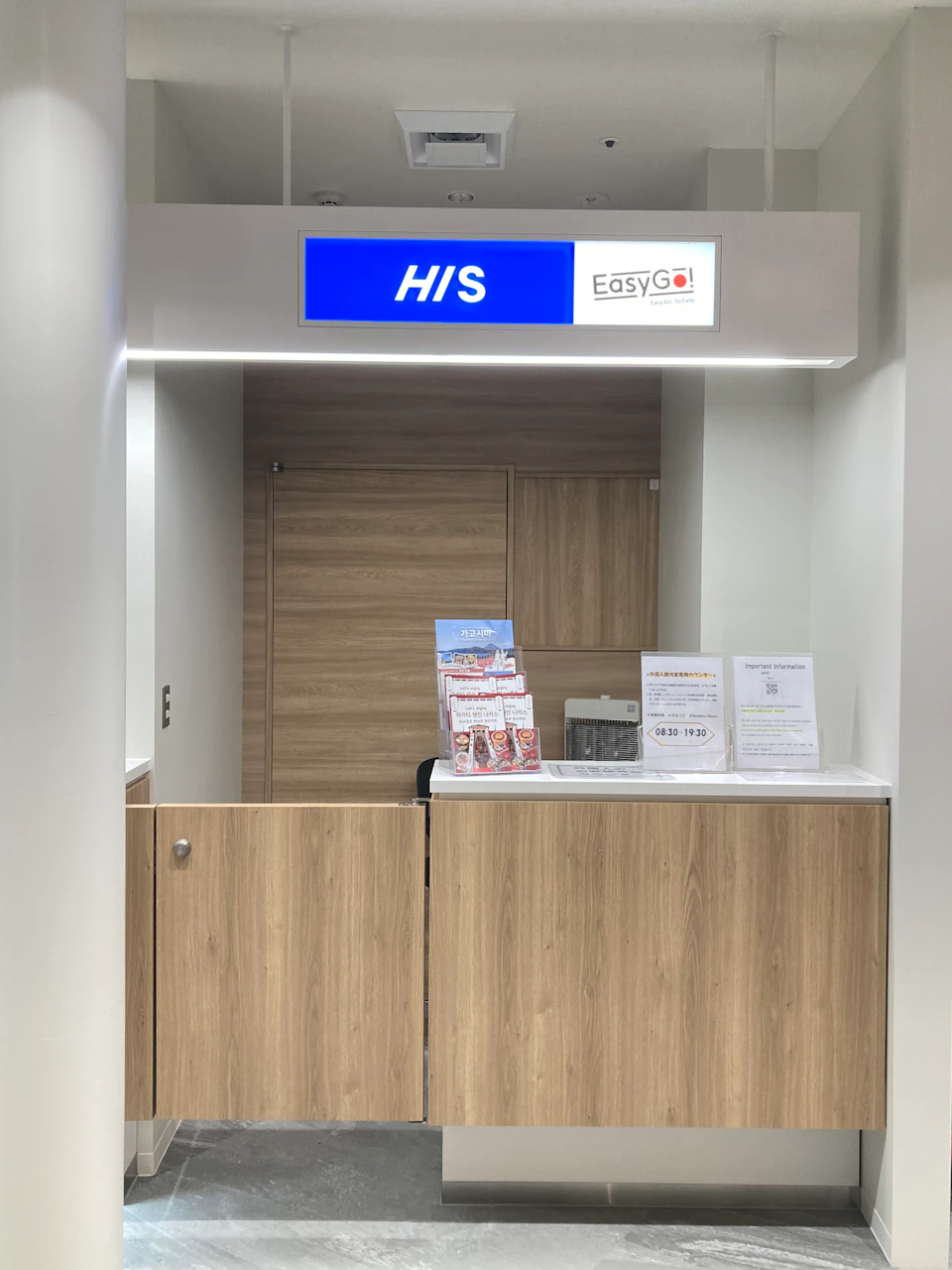 A reception counter with a wooden finish under a sign reading 'HIS' and 'EasyGo!' Various informational materials are displayed.
