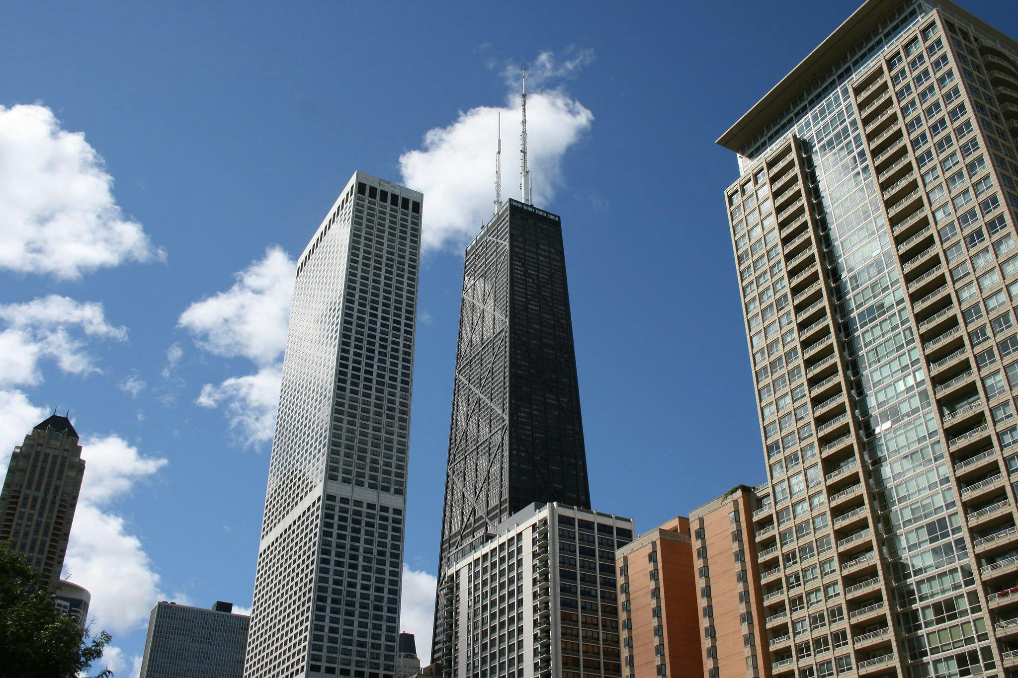 晴れやかな青空にそびえ立つ高層ビル。雲が散在しています。