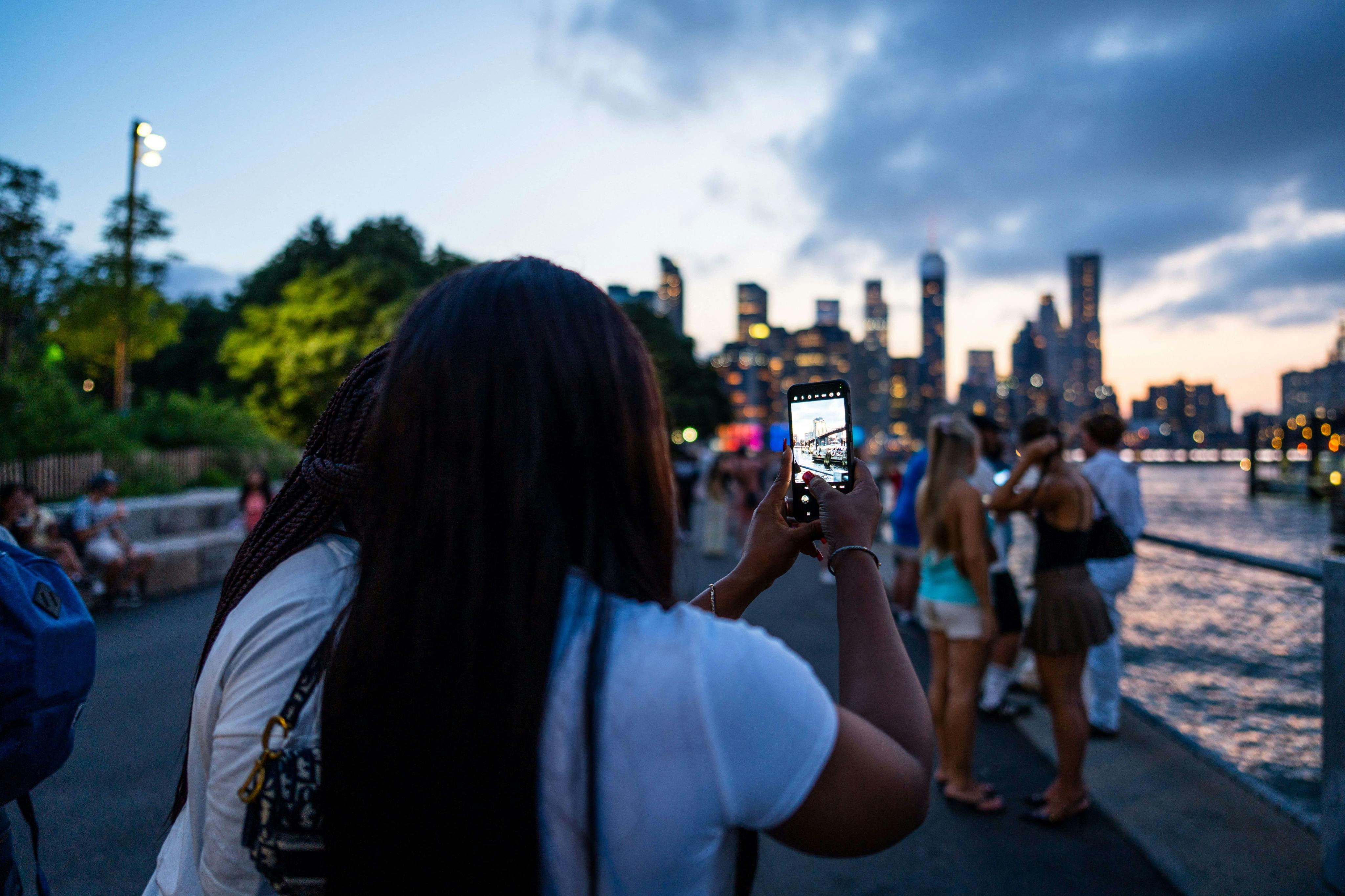 해질 무렵 수많은 사람들과 함께 도시의 스카이라인을 촬영하는 사람.