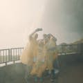 A group on a viewing platform at the Journey Behind the Falls Experience, posing for a photo with Horseshoe Falls behind them