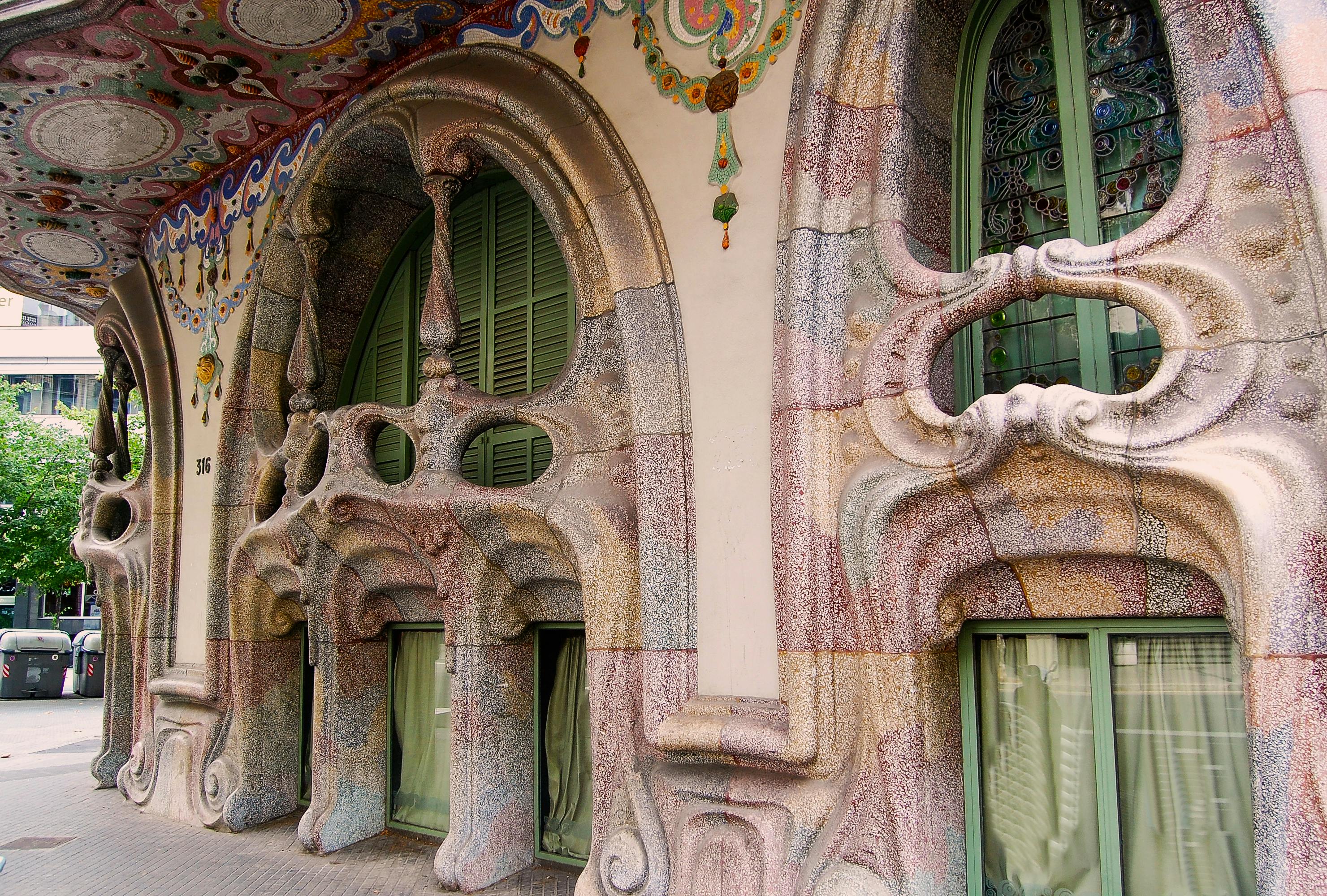 装饰华丽的建筑立面，配有弯曲的窗户、精致的石雕和精致的拱门下色彩缤纷的马赛克设计。