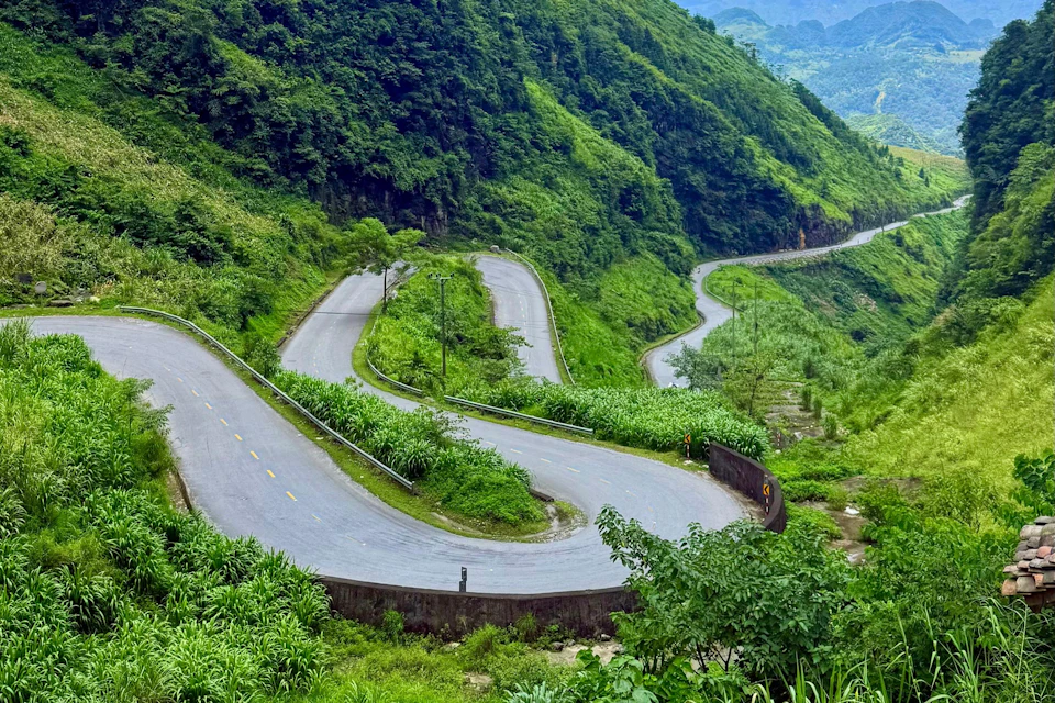 A winding mountain road with sharp bends surrounded by lush green vegetation and trees.