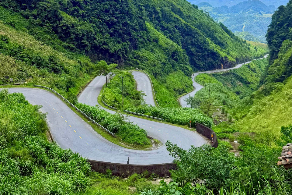 A winding mountain road with sharp bends surrounded by lush green vegetation and trees.
