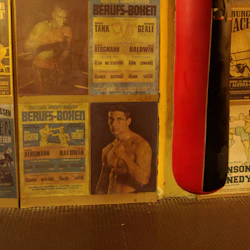 Gamla boxningsposters på en gul vägg nära en röd boxningssäck.