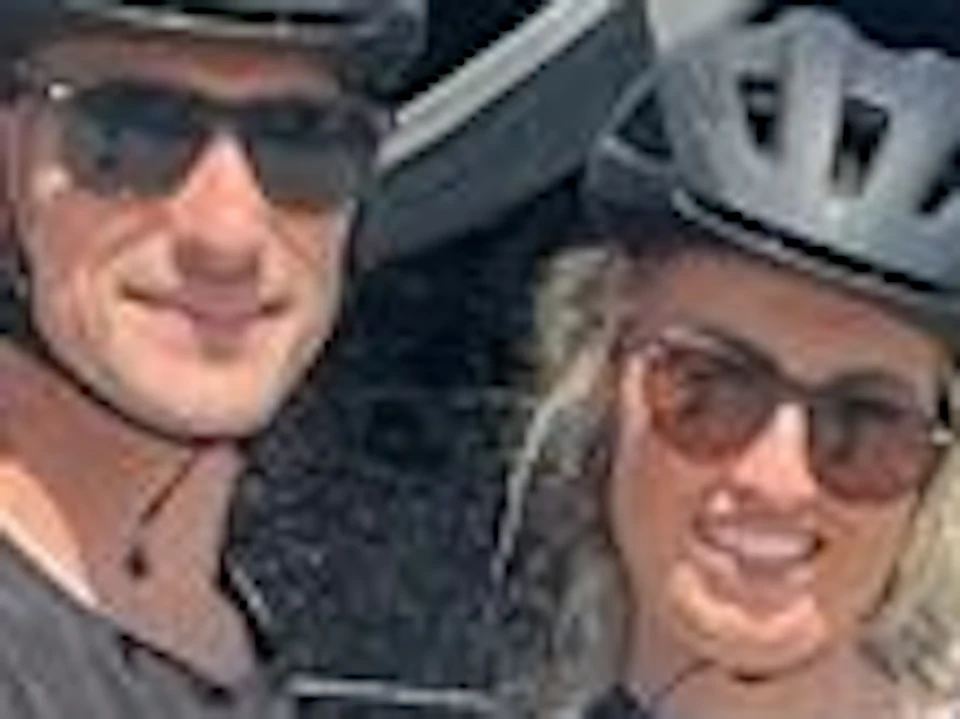 Two people wearing helmets stand with bicycles in front of the "Star of India" ship docked at a harbor on a sunny day.
