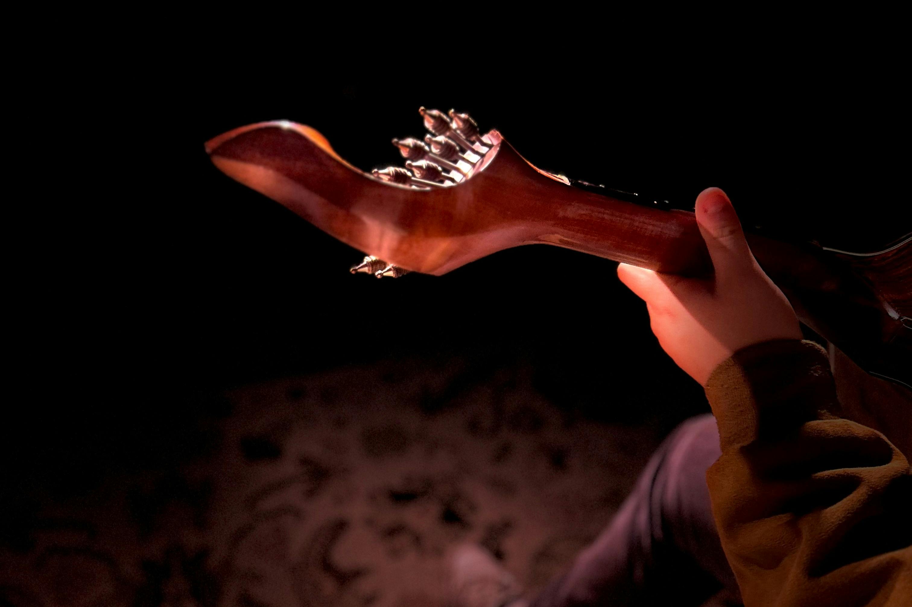 Ένα χέρι που κρατάει το λαιμό μιας κιθάρας σε χαμηλό φωτισμό.