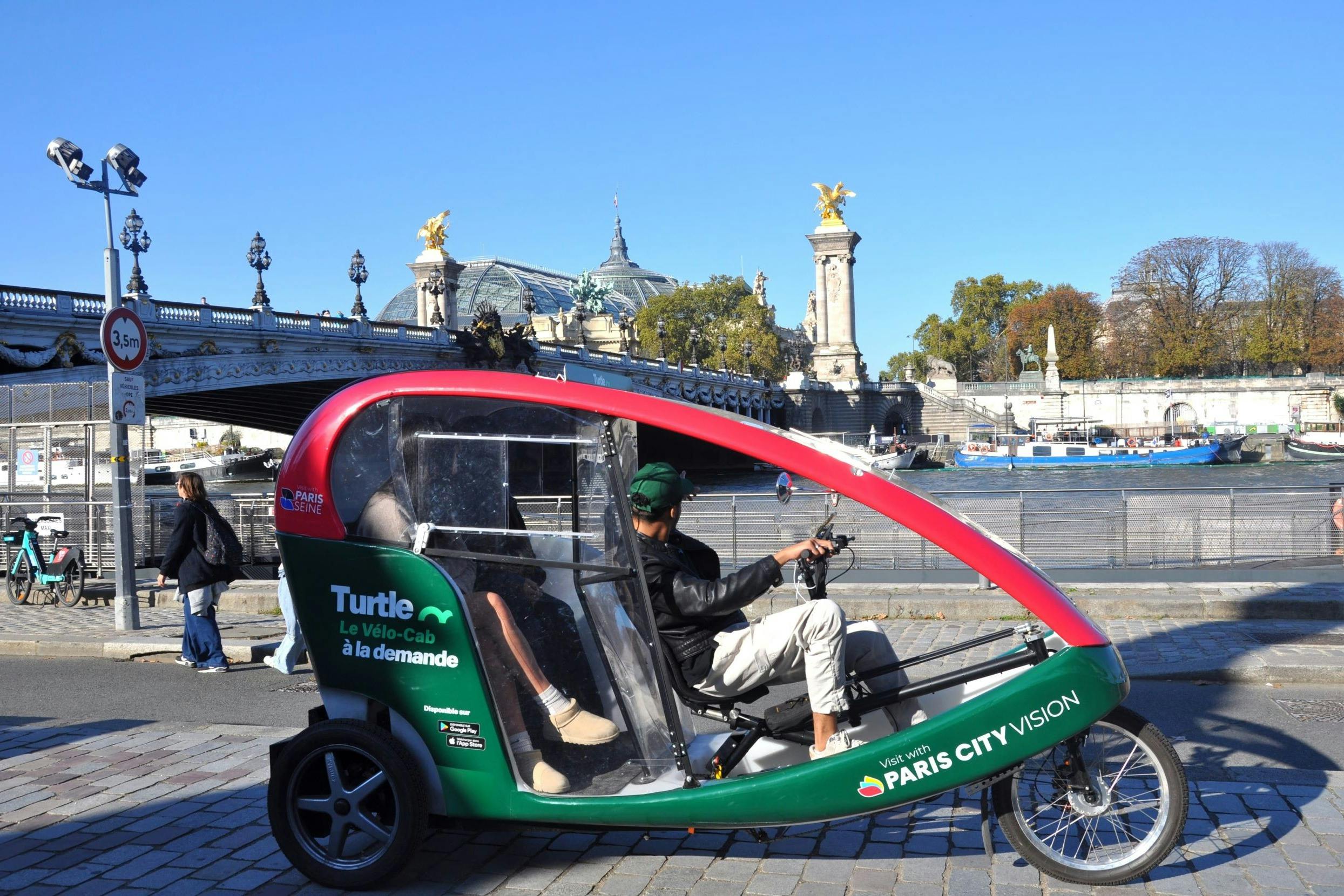 Человек едет на зелено-красном педикюре с брендом «Paris City Vision» рядом с мостом, украшенным статуями в городской обстановке.