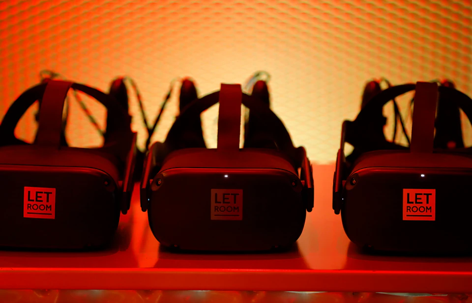 Three virtual reality headsets on a shelf, illuminated by an orange light.
