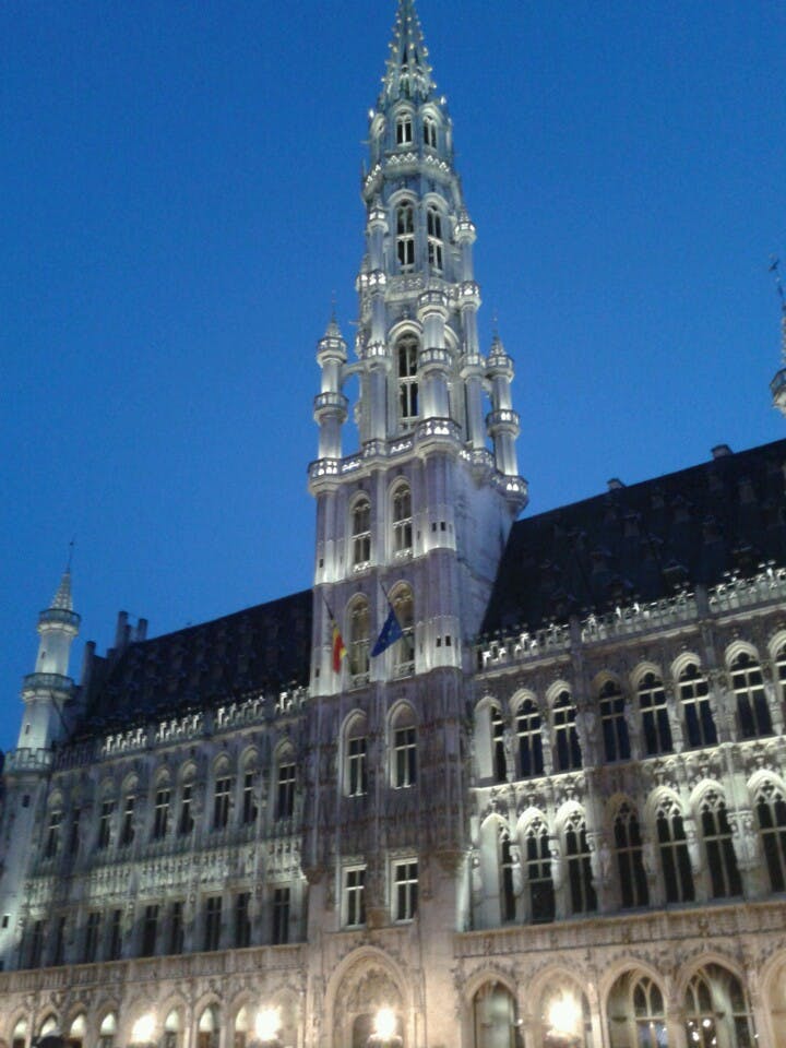 Upplyst byggnad i gotisk stil med en hög, utsmyckad spiral mot en klar kvällshimmel.