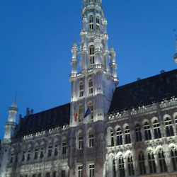 Upplyst byggnad i gotisk stil med en hög, utsmyckad spiral mot en klar kvällshimmel.