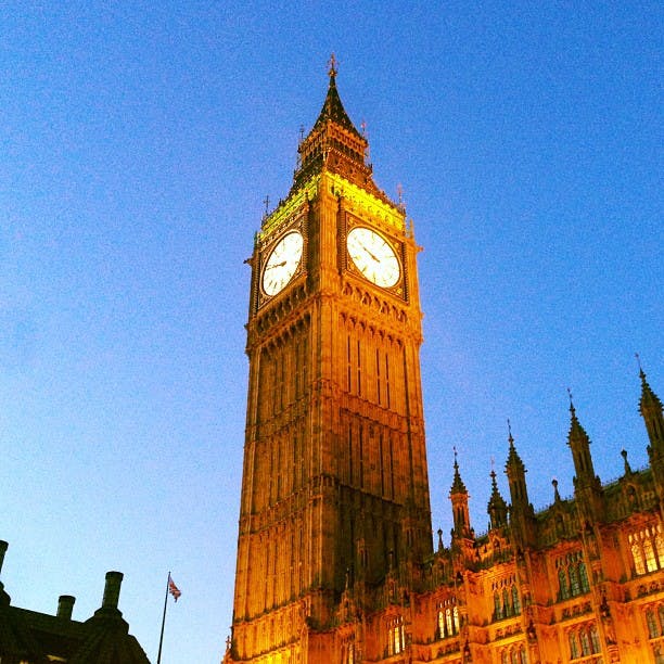 Klocktornet i Big Ben lyste mot en klarblå himmel med intilliggande historiska byggnader synliga.