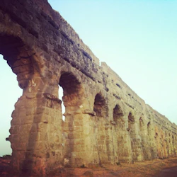 Forntida stenakvedukt med flera valv under en klar himmel.