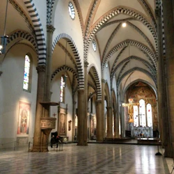 Katedralinteriör med högt välvt tak, randiga valv, glasmålningar och ett altare med ett stort krucifix.